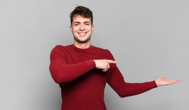 Genç adam gülümsüyor, mutlu, kaygısız ve memnun, fotokopi alanındaki konsepte ya da fikre işaret ediyor.