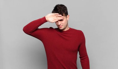 Genç adam stresli, yorgun ve hayal kırıklığına uğramış görünüyor, alnından ter damlıyor, umutsuz ve bitkin hissediyor.