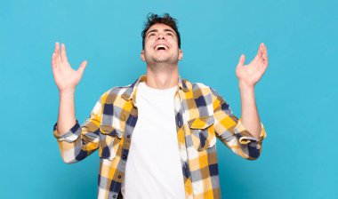 Genç adam mutlu, şaşkın, şanslı ve şaşırmış hissediyor, zaferi kutluyor, iki eli havada.