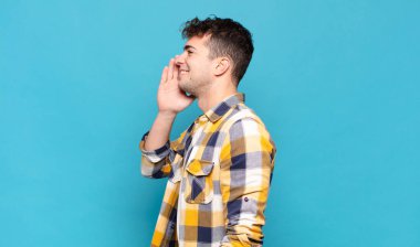 Genç adam profil görüntüsü, mutlu ve heyecanlı görünüyor, bağırıyor ve kenardaki boşluğu kopyalamak için arıyor