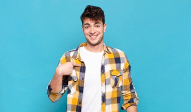 Genç adam mutlu, gururlu ve şaşırmış görünüyor, neşeli bir şekilde kendini gösteriyor, kendinden emin ve yüce hissediyor.