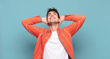 Genç adam gülümsüyor ve rahatlıyor, tatmin oluyor, kaygısız, neşeli ve rahatlatıcı.