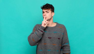 Genç adam sessizlik ve sessizlik istiyor, parmaklarıyla ağzının önünde işaret ediyor, 