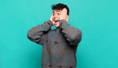 Genç adam mutlu, heyecanlı ve şaşırmış hissediyor, iki eli yüzü yana bakıyor.