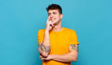 Genç adam mutlu bir şekilde gülümsüyor ve hayal kuruyor ya da şüphe ediyor.