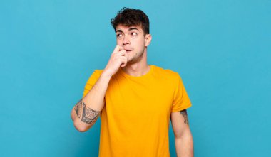 Şaşırmış, gergin, endişeli ya da korkmuş bakışları olan genç bir adam kopya uzayına bakıyor.