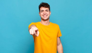 Genç adam kameraya tatmin olmuş, kendinden emin, dostane bir gülümsemeyle bakıyor ve seni seçiyor.