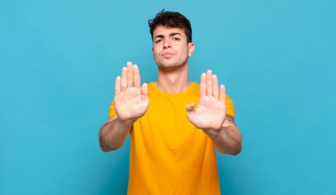 Genç adam ciddi görünüyor, mutsuz, kızgın ve hoşnutsuz giriş yasaklandı ya da her iki avuçta da dur diyor.