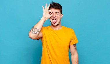 Genç adam mutlu bir şekilde gülümsüyor, şaka yapıyor ve gözetleme deliğinden bakıyor, sırları gözetliyor.