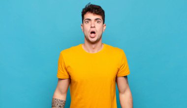 Genç adam şok olmuş ya da şaşırmış görünüyor, ağzı açık bir şekilde 