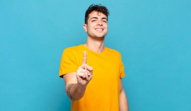 Genç adam gururla gülümsüyor ve gururla bir numaralı pozunu veriyor, kendini lider gibi hissediyor.