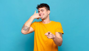 Genç adam neşeyle gülümsüyor ve kamerayı işaret ediyor. Sonra seni arıyor, telefonla konuşuyor.