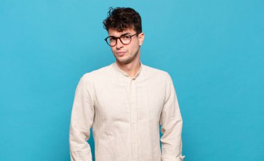 Genç adam gururlu, kendinden emin, havalı, küstah ve küstah görünüyor, gülümsüyor, başarılı hissediyor.