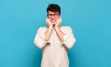 Genç adam sinirli, stresli ve sinirli görünüyor, iki kulağını da sağır edici bir ses, ses ya da yüksek sesle kapatıyor.