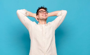 Genç adam gülümsüyor ve rahatlıyor, tatmin oluyor, kaygısız, neşeli ve rahatlatıcı.