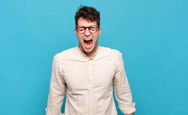 Genç adam agresif bir şekilde bağırıyor, çok kızgın, hayal kırıklığına uğramış, öfkeli ya da sinirli görünüyor.