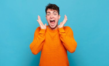 Genç adam beklenmedik bir sürprizden dolayı şaşkın, heyecanlı, gülen, şaşkın ve mutlu hissediyor.