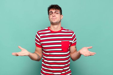 Genç adam şaşkın ve şaşkın hissediyor, doğru cevap veya karardan emin değil, bir seçim yapmaya çalışıyor.