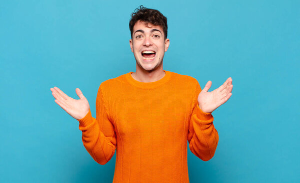 Молодой человек выглядит счастливым и взволнованным, шокированным неожиданным сюрпризом с открытыми обеими руками рядом с лицом к лицу