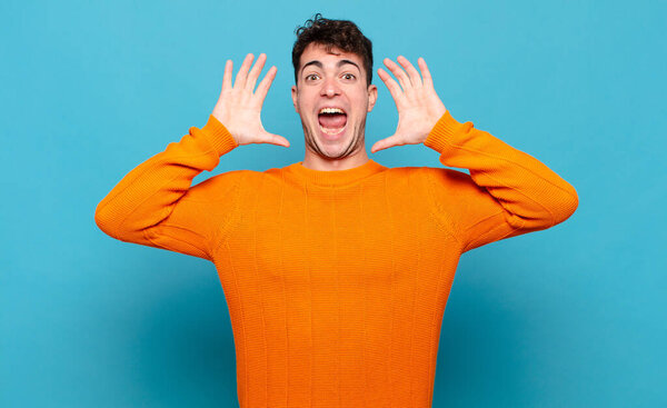 молодой человек кричит с поднятыми вверх руками, чувствуя ярость, разочарование, стресс и расстройство