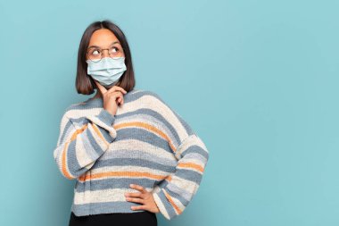 Genç İspanyol kadın mutlu bir şekilde gülümsüyor ve hayal kuruyor ya da şüphe ediyor.