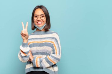 Genç İspanyol kadın gülümsüyor ve arkadaş canlısı görünüyor. İki ya da iki numarayı gösteriyor. Elleri önde, geri sayıyor.