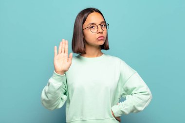 Genç İspanyol kadın ciddi, sert, hoşnutsuz ve kızgın görünüyor. Avuç içinin açık olması jesti durduruyor.