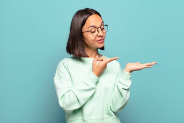 Genç İspanyol kadın gülümsüyor, mutlu, kaygısız ve tatmin olmuş hissediyor, fotokopi alanındaki konsepte ya da fikre işaret ediyor.