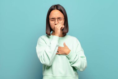 Boğazı ağrıyan ve grip belirtileri gösteren ağzı kapalı öksüren genç İspanyol kadın.