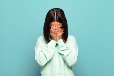 Genç İspanyol kadın üzgün, hayal kırıklığına uğramış, gergin ve depresif, iki eliyle yüzünü kaplayan, ağlayan