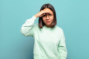 Genç İspanyol kadın şaşkınlık ve şaşkınlık içinde bakıyor, el üstünde uzak bakıyor, izliyor ya da arıyor.