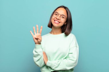 Genç İspanyol kadın gülümsüyor ve arkadaş canlısı görünüyor. Elleri önde, geriye doğru sayıyor.