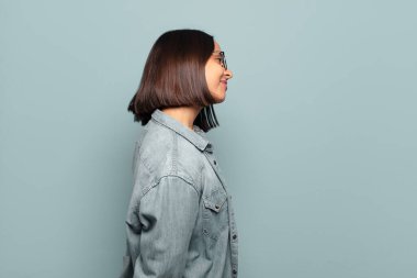 Profil görünümlü genç İspanyol kadın uzayı kopyalamaya çalışıyor, düşünüyor, hayal ediyor ya da hayal kuruyor.