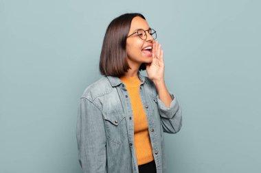 Genç İspanyol kadın profil görüşü, mutlu ve heyecanlı görünüyor, bağırıyor ve kenardaki boşluğu kopyalamak için arıyor