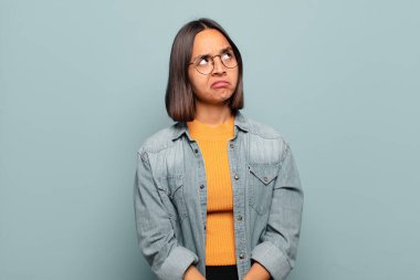 Genç İspanyol kadın şaşkın ve şaşkın görünüyor, merak ediyor veya bir sorunu çözmeye çalışıyor veya düşünüyor.