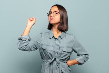 Genç İspanyol kadın ciddi, güçlü ve isyankar hissediyor, yumruğunu kaldırıyor, protesto ediyor ya da devrim için savaşıyor.