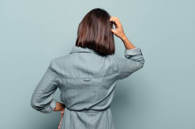 Genç İspanyol kadın bilgisiz ve şaşkın hissediyor, bir çözüm düşünüyor, eli kalçasında, diğeri kafasında, dikiz aynasından.