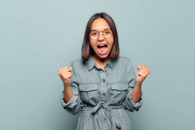 Genç İspanyol kadın mutlu, pozitif ve başarılı hissediyor, zaferi, başarıları veya iyi şansı kutluyor.