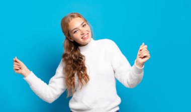 Güzel sarışın kadın gülümsüyor, kaygısız hissediyor, rahatlamış ve mutlu, dans ediyor ve müzik dinliyor, bir partide eğleniyor.