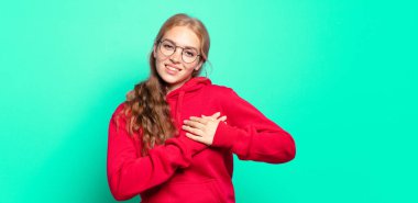 Sarışın, güzel bir kadın romantik, mutlu ve aşık, neşeyle gülümseyen ve kalbe yakın el ele tutuşan.