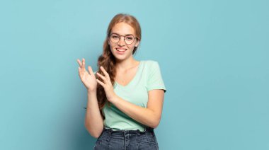 Sarışın, güzel bir kadın mutlu ve başarılı hissediyor, gülümsüyor ve alkışlıyor, alkışlarla tebrik ediyor.