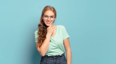 Güzel sarışın kadın gülümsüyor, hayattan zevk alıyor, mutlu, arkadaş canlısı, tatmin olmuş ve tasasız.