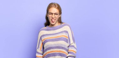 Sarışın, güzel bir kadın tiksinmiş ve rahatsız olmuş hissediyor, dilini dışarı çıkarıyor, iğrenç ve iğrenç bir şeyden hoşlanmıyor.