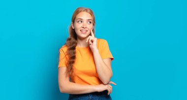 Sarışın, güzel bir kadın mutlu bir şekilde gülümsüyor ve hayal kuruyor ya da şüphe ediyor.