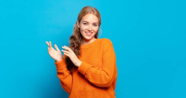 Sarışın, güzel bir kadın mutlu ve başarılı hissediyor, gülümsüyor ve alkışlıyor, alkışlarla tebrik ediyor.