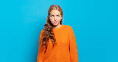 Sarışın, güzel bir kadın üzgün, üzgün ya da kızgın ve olumsuz bir tavır takınıyor, anlaşmazlık içinde kaşlarını çatıyor.