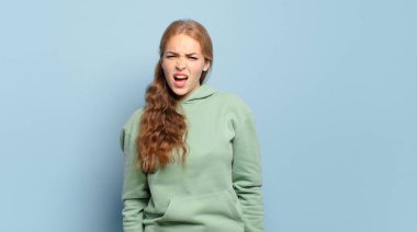 Sarışın, güzel bir kadın agresif bir şekilde bağırıyor, çok sinirli, sinirli, öfkeli ya da sinirli görünüyor.