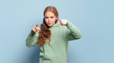 Sarışın, güzel bir kadın kamerayı iki parmağıyla ve kızgın bir ifadeyle sana görevini yapmanı söylüyor.