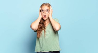 Sarışın, hoş olmayan güzel bir kadın. Şok olmuş, korkmuş ya da endişeli görünüyor. Ağzı sonuna kadar açık ve iki kulağını da eliyle kapatıyor.