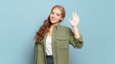 Sarışın, güzel bir kadın gülümsüyor ve arkadaş canlısı görünüyor, 5 ya da 5 numarayı gösteriyor, elleri önde, geriye doğru sayıyor.